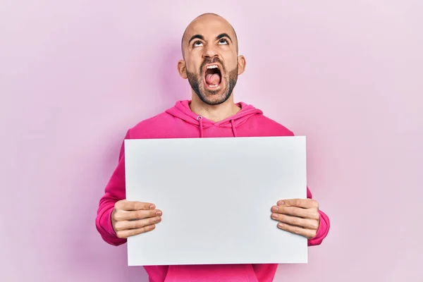 Young Bald Man Holding Blank Empty Banner Angry Mad Screaming — Zdjęcie stockowe