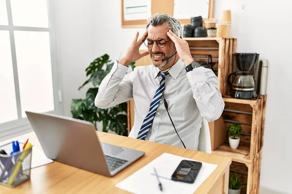 ストレスが原因で頭の痛みのために頭の上に手でオペレーターヘッドセットを身に着けているオフィスで働く中年のパニックビジネスマン 片頭痛 — ストック写真