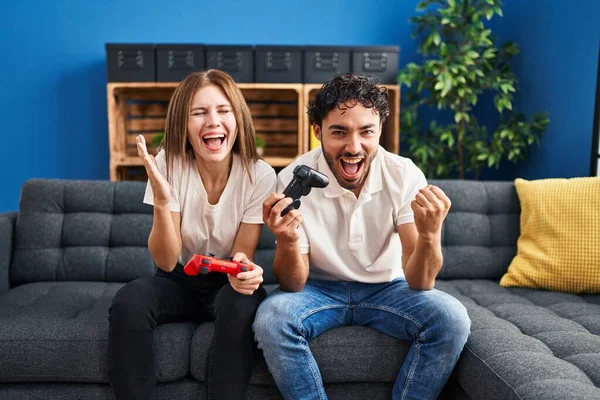Young Couple Playing Video Game Holding Controller Home Celebrating Victory — Fotografia de Stock