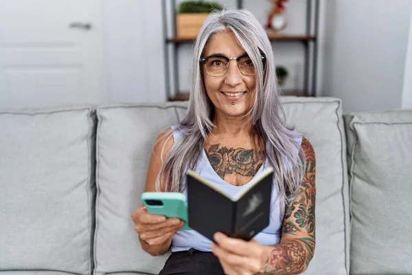 在家里使用智能手机持护照的中年灰发妇女 — 图库照片
