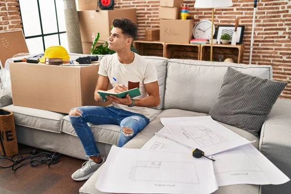 Jonge Spaanse Man Schrijft Notitieboekje Nieuw Huis — Stockfoto