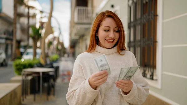 Junge Rothaarige Frau Lächelt Zuversichtlich Beim Dollarzählen Auf Der Straße — Stockfoto