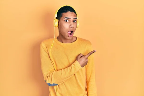 Junge Afrikanisch Amerikanische Kerl Musik Hören Mit Kopfhörern Überrascht Zeigen — Stockfoto