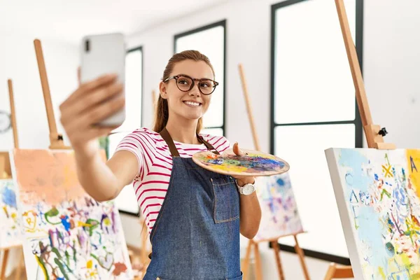 年轻女子面带微笑 自信地在艺术工作室的智能手机前自拍 — 图库照片