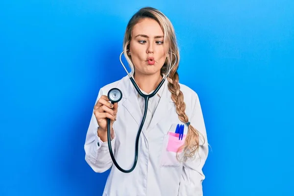 Beautiful Young Blonde Doctor Woman Holding Stethoscope Making Fish Face — Stok fotoğraf