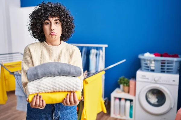 Young Brunette Woman Curly Hair Holding Clean Laundry Depressed Worry — Stockfoto