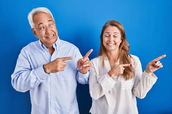Middle Age Hispanic Couple Standing Blue Background Pointing Aside Worried — Stockfoto