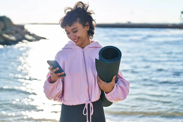 Young Woman Holding Yoga Mat Using Smartphone Seaside — Foto de Stock