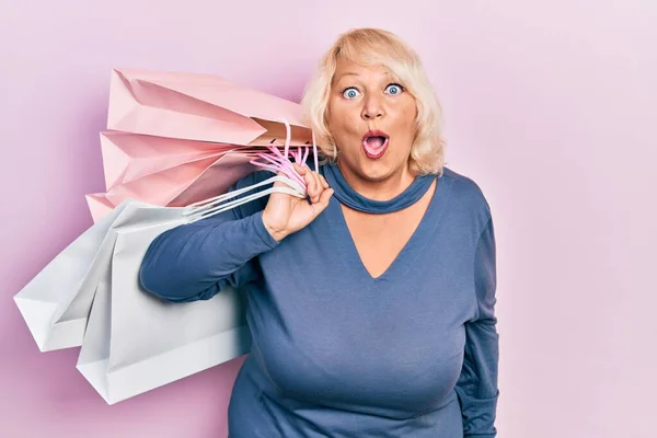 Middle Age Blonde Woman Holding Shopping Bags Scared Amazed Open — Photo