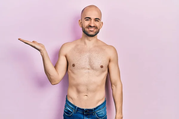 Young Bald Man Standing Shirtless Smiling Cheerful Presenting Pointing Palm — Stock fotografie