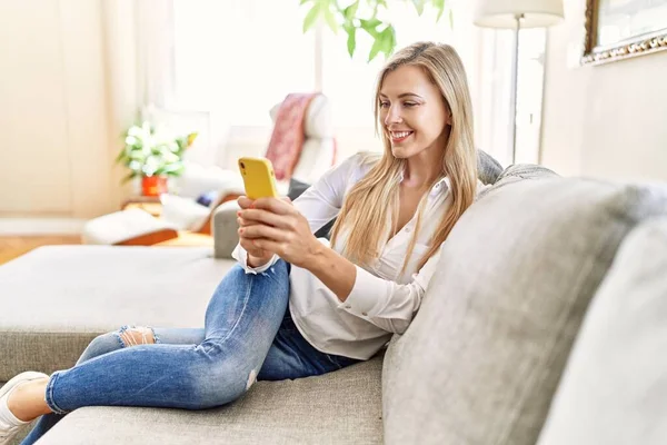 Mujer Rubia Joven Usando Teléfono Inteligente Sentado Sofá Casa — Foto de Stock