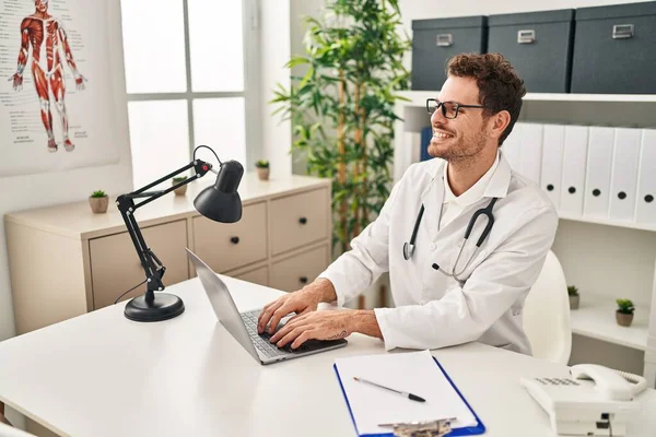 Young Hispanic Man Wearing Doctor Uniform Using Laptop Clinic — Stock fotografie