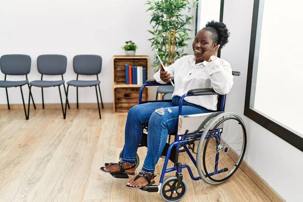 Young Black Woman Sitting Wheelchair Waiting Room Smiling Doing Phone —  Fotos de Stock