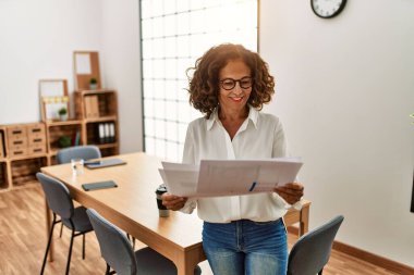 Ofiste çalışırken gülümseyen orta yaşlı İspanyol kadın.