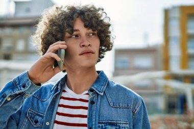 Genç İspanyol adam şehirde telefonla konuşuyor.