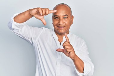 Orta yaşlı, sıradan kıyafetler giyen, gülümseyen, elleri ve parmakları gülen yüzlü bir adam. yaratıcılık ve fotoğrafçılık kavramı. 