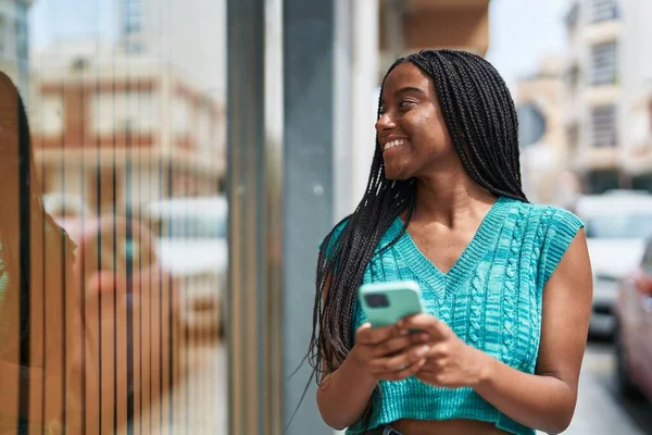 アフリカ系アメリカ人の女性が路上でスマートフォンを使って笑顔で — ストック写真