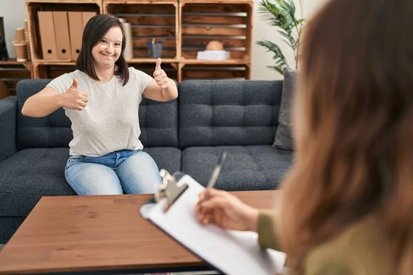 Hispanic girl with down syndrome doing therapy approving doing positive gesture with hand, thumbs up smiling and happy for success. winner gesture.