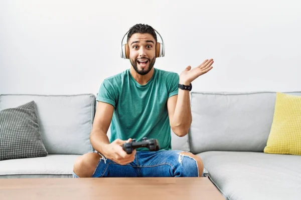 Handsome Hispanic Man Wearing Headphones Playing Video Game Holding Controller — 图库照片