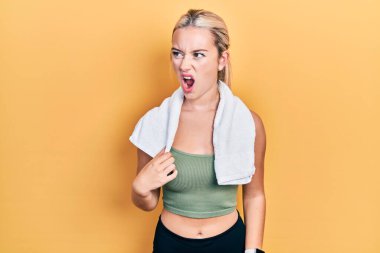 Spor kıyafetleri ve havlu giyen genç sarışın kız kızgın ve kızgın çığlık atıyor ve öfkeden köpürüyor, öfkeden bağırıyor. öfke ve agresif konsept. 