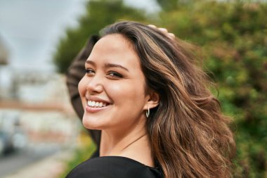 Genç İspanyol kadın gülümseyerek şehirde mutlu mesut dikiliyor..