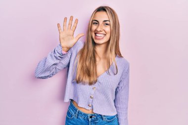 Güzel İspanyol kadın gündelik tişört giyer ve beş numarayı göstererek gülümserken kendinden emin ve mutlu olur.. 