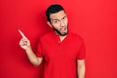 Sakallı, ağzı açık gezen, şüpheci ve iğneleyici bakışlı, parmaklarını yana doğru gösteren İspanyol bir adam. 