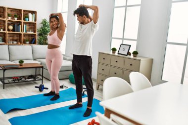 Genç Latin sporcu çift gülümseyerek evde mutlu bir antrenman yapıyor..