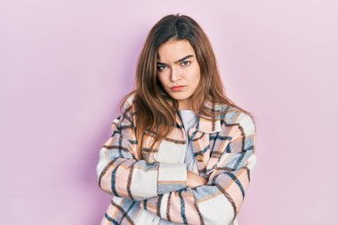 Gündelik kıyafetler giyen, kuşkucu ve gergin genç beyaz bir kız. Yüzünde çapraz kollarla onaylamayan bir ifade var. negatif kişi. 