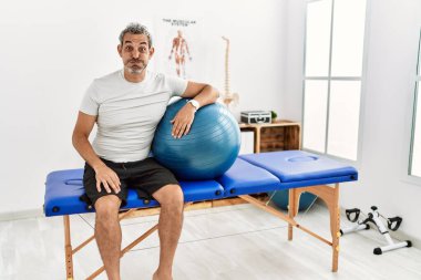 Orta yaşlı İspanyol bir adam ağrı kesici kliniğinde elinde komik suratıyla pilates topu şişiren yanaklar tutuyor. Havayla şişmiş ağız, çılgın bir ifade.. 