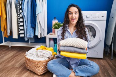 Genç esmer kadın temiz çamaşırları tutuyor. Çılgınca kutlama yapıyor ve başarıya hayret ediyor. Gözleri açık, heyecanlı çığlıklar atıyor.. 