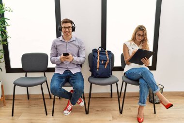 İki İspanyol mutlu bir şekilde gülümsüyor. Bekleme odasında akıllı telefon kullanıyor.