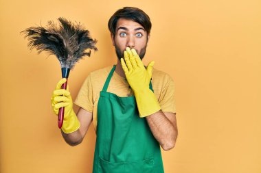 Önlük takan İspanyol genç adam temizlikçi ağzını eliyle kapadı, şok oldu ve hata yapmaktan korktu. şaşırmış ifade 