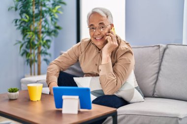 Son sınıf öğrencisi akıllı telefonda konuşuyor. Evde touchpad izliyor.