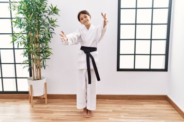 Karate kimonosu ve siyah kuşak giyen genç İspanyol kız kameraya sarılıp gülümsüyor. Mutluluğu kucaklayan neşeli bir ifade.. 
