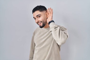 Soyutlanmış arka planda dikilen yakışıklı genç adam kulağına fısıldayarak dedikoduları ve dedikoduları dinliyor. Sağırlık kavramı. 