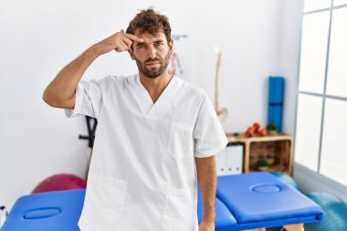 Ağrı kesici kliniğinde çalışan genç yakışıklı fizyoterapist alnındaki sivilceden mutsuz olduğunu gösteriyor, siyah noktalı çirkin bir enfeksiyon. sivilce ve deri problemi 