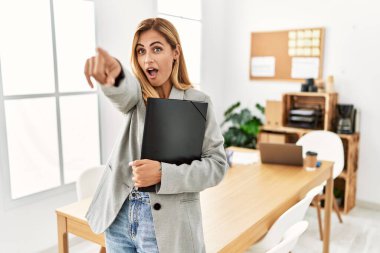 Ofisteki sarışın iş kadını parmaklarıyla işaret ederek şaşırmış, ağzı açık şaşkın, ön tarafta bir şey var. 