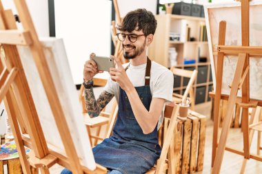 Genç İspanyol ressam resim stüdyosunda akıllı telefon çizimiyle resim yapıyor..