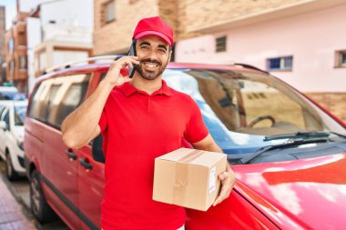 Genç İspanyol kurye caddedeki akıllı telefon paketinden konuşuyor.