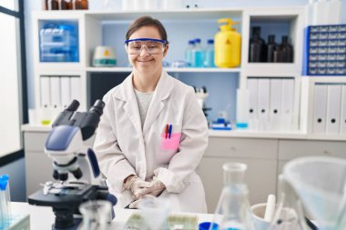 Down sendromlu İspanyol kız mutlu ve havalı bir gülümsemeyle bilim adamı laboratuarında çalışıyor. şanslı kişi. 