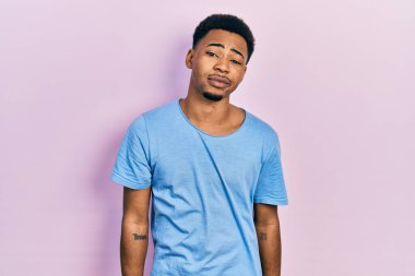 Genç Afro-Amerikalı adam günlük mavi tişört giyiyor. Uykulu ve yorgun görünüyor. Yorgun ve akşamdan kalma, tembel gözlü.. 