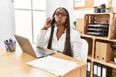 Ofiste örgü ören zenci bir kadın telefonda komik suratlı yanaklarıyla konuşuyor. Havayla şişmiş ağız, çılgın bir ifade.. 