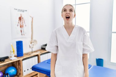 Ağrı giderme kliniğinde çalışan genç, beyaz bir kadın kızgın ve öfkeli bağırıyor, öfkeyle bağırıyor. öfke ve agresif konsept. 