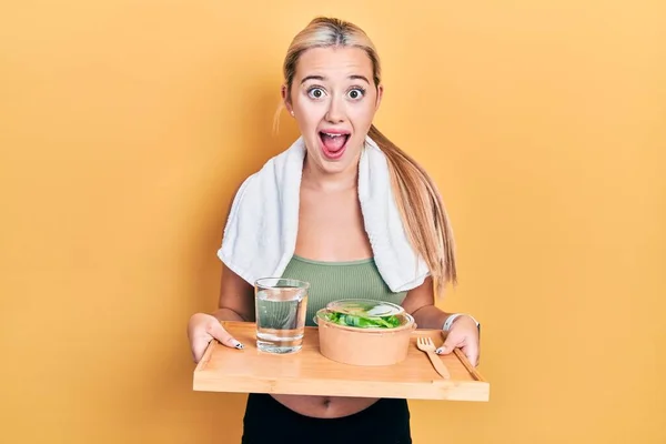 Young Blonde Girl Wearing Sportswear Eating Healthy Food Celebrating Crazy — 스톡 사진