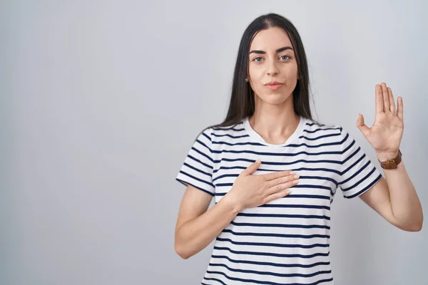 Young Brunette Woman Wearing Striped Shirt Swearing Hand Chest Open — стоковое фото