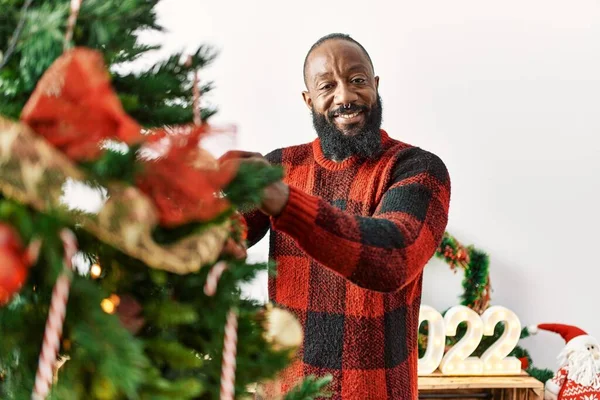 Young african american man smiling confident decorating christmas tree at home