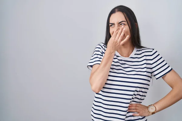 Young Brunette Woman Wearing Striped Shirt Smelling Something Stinky Disgusting — ストック写真