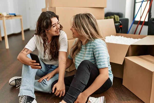 Pareja Joven Sonriendo Feliz Usando Teléfono Inteligente Nuevo Hogar —  Fotos de Stock