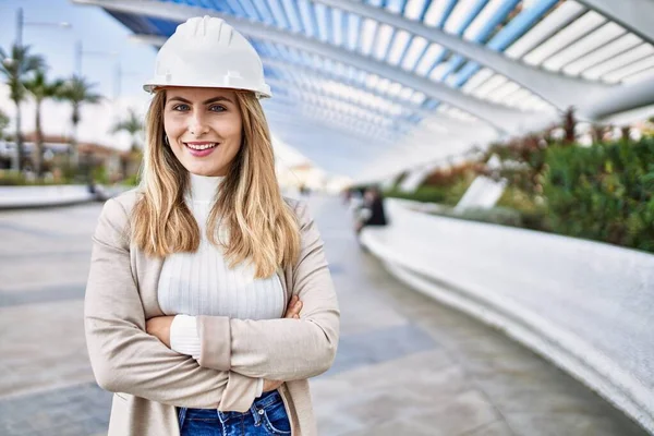 Young blonde woman smiling confident wearing hardhat at street